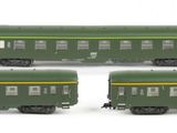 four green train cars are lined up on a white surface