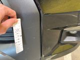 a hand that is holding a piece of paper near the front door of a car