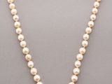 a white pearl necklace with a diamond clasp