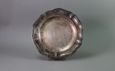 an antique silver plate on a stand against a gray background
