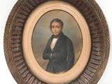 portrait d'un homme en costume noir et nœud papillon, dans un cadre en bois