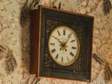 une horloge accrochée au mur au-dessus d'un tableau représentant des oiseaux