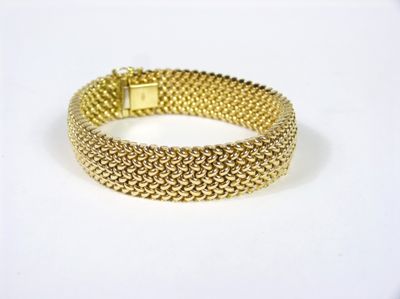 gros plan d'un bracelet en or sur une surface blanche