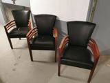 trois fauteuils en cuir noir avec des accoudoirs en bois dans une pièce