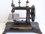 une machine à coudre noire et dorée posée sur une surface blanche