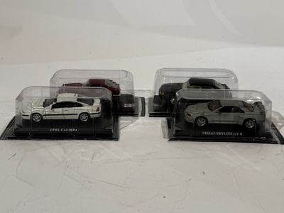 trois petites voitures dans une vitrine posée sur une surface blanche