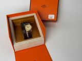 une boîte orange contenant une montre, posée sur une surface blanche