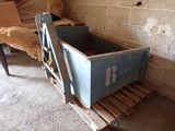 une caisse bleue posée sur une palette à côté d'une chaise