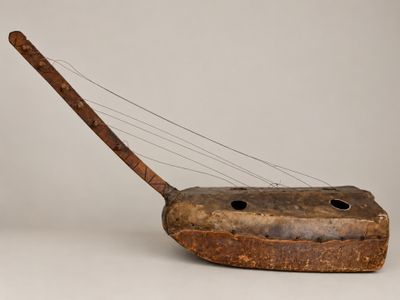 an old wooden instrument with a wooden handle on a white surface