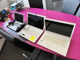 deux ordinateurs portables posés sur une table rose