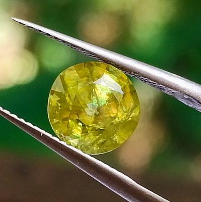 a close up of a yellow diamond being held by a pair of pliers