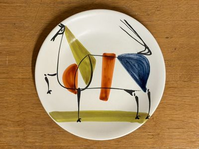 a plate with a painting on it on a wooden table
