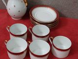many cups and saucers sitting on a red table