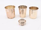 three silver cups and a silver strainer on a white surface