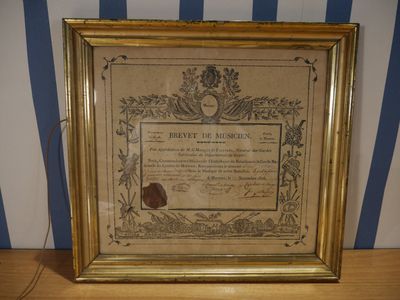 une vieille photo encadrée représentant un certificat, posée sur une table en bois