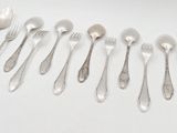 six forks and spoons are arranged in a row on a white surface