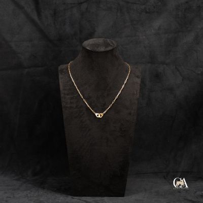 un collier en or posé sur un socle de mannequin, sur fond noir