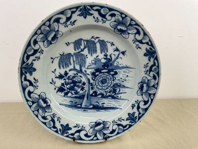 une assiette bleue et blanche décorée d'un arbre et de fleurs