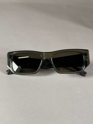 une paire de lunettes de soleil noires posée sur une surface blanche