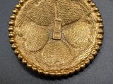 a close up of a gold pendant with a cross on it