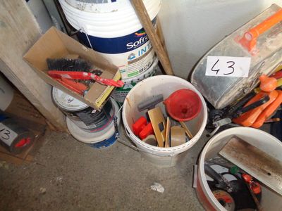 Plusieurs seaux remplis d'outils sont posés par terre à côté d'un seau de peinture
