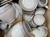 a cardboard box full of white and gold china