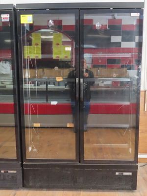 un homme debout devant un réfrigérateur dans un magasin