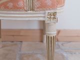 a small chair with a pink cushion and a vase on it