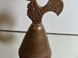 a metal bell with a bird on top of it