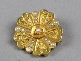 une photo en gros plan d'une broche ornée de perles