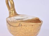 a gold saucer with a spoon in the shape of a bird