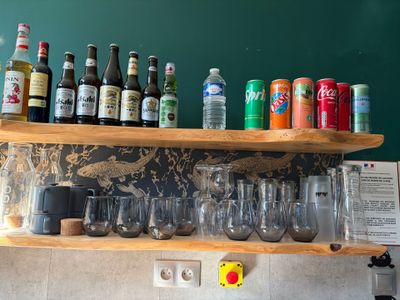 many bottles and glasses on a shelf above a sink
