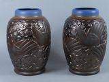 two brown vases with blue lids on a gray surface