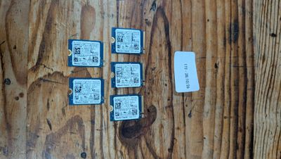 quatre cartes micro SD posées sur une table en bois, à côté d'une feuille de papier