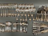 a lot of silver spoons and forks laid out on a table