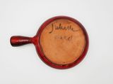 an old red pot with writing on it sitting on a white surface