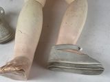 a wooden doll sitting on the floor next to a pair of shoes