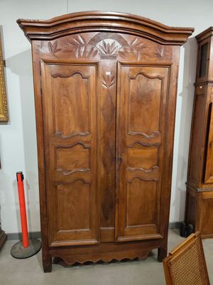 une armoire en bois dans une pièce où est accrochée une horloge au mur