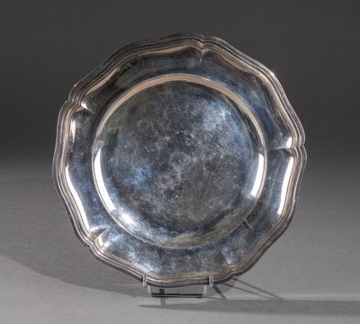 un plat ancien en argent posé sur un socle, sur fond gris