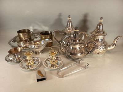 un service à thé en argent posé sur une table, à côté d'autres objets en argent