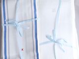 three folded towels with blue ribbons tied to them on a table