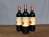 three bottles of red wine sitting on top of a wooden table