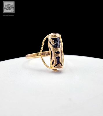 gros plan d'une bague en or contenant une pierre noire