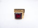 a close up of a red stone ring on a white surface