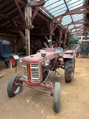 un tracteur rouge garé dans une grange au toit de verre