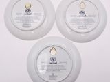 three white plates with a logo on them sitting on a white surface