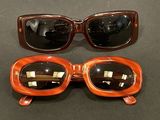 two pairs of sunglasses sitting on top of a table next to each other