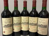 six bottles of wine are lined up on a table