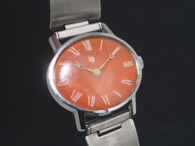 une montre orange dont le cadran est orné de chiffres romains