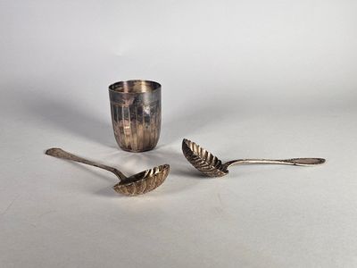 deux cuillères et une tasse posées sur une table, sur fond blanc